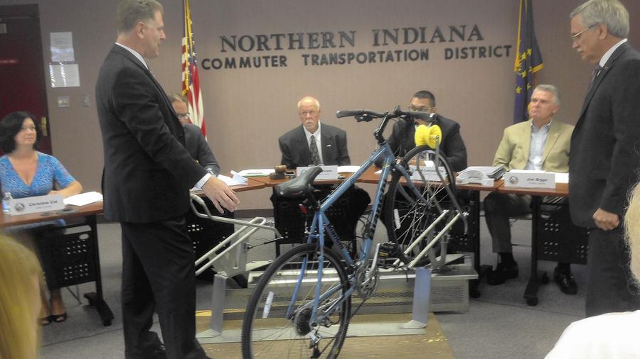 Mike Noland, general manager for the South Shore Line commuter rail, demonstrates a bike rack from SportWorks, the same company that makes bike racks for CTA and Pace buses. Photo: Carole Carlson