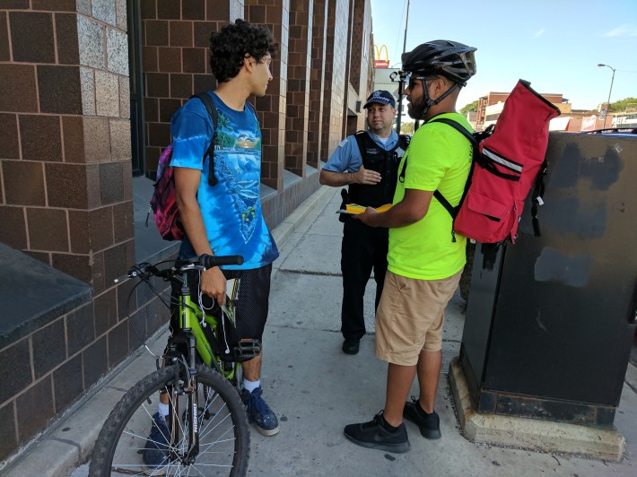 CDOT Bicycling Ambassador Jose Briceno and an officer from the 20th District talk with a cyclist during a recent outreach event in Lincoln Square. Photo: CDOT