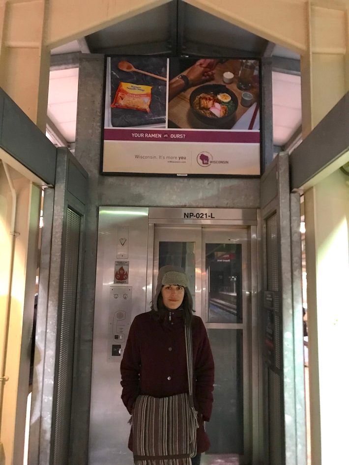 Marta Grabowski by a Wisconsin ad playing up the lower cost of living in the Badger State, asking "Your ramen or ours." Photo: John Greenfield