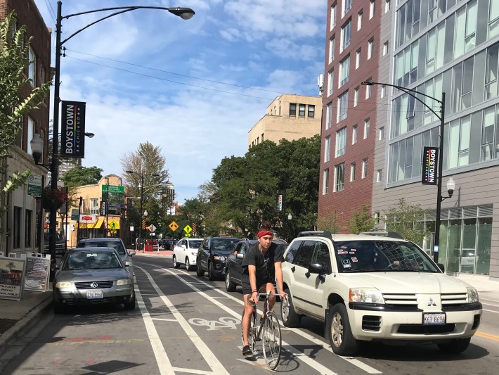 A cyclist uses adouble-buffered bike lane as intended, cycling in the center of the bikeable area, in the middle of the arrow. A more time rider might cycle closer to parked cars. Photo: John Greenfield