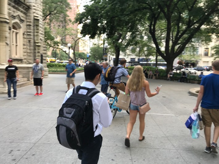 A Divvy user rides across the old Water Tower pedestrian plaza. Photo: John Greenfield