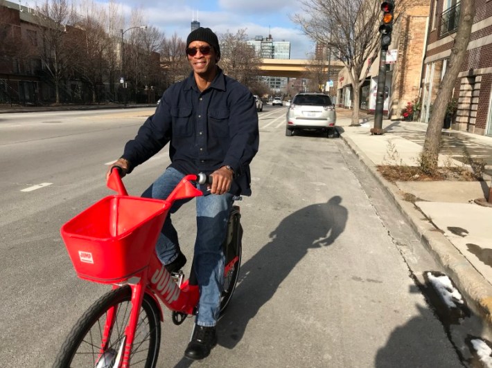 Arron Muhammad, owner of Akhira's Praline, Candy & Coffee House, test rides a Jump bike. Photo: John Greenfield