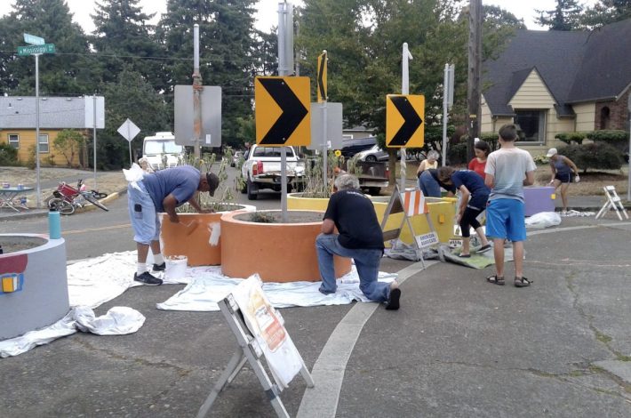Neighbors paint traffic diverter planters in Portland. This infrastructure requires drivers to turn off the street instead of using it as a cut-through route, but allows bicyclists to keep going straight. Photo: Jonathan Maus, Bike Portland