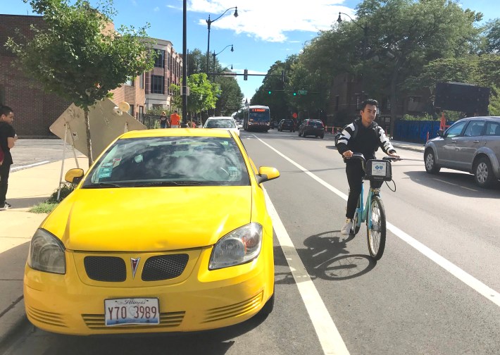 A cyclist rides about with his wheels about two feet away from the travel lane, three feet from the parking lane, on a five-foot-wide bike lane on Halsted in Chicago's Lincoln Park neighborhood. Photo John Greenfield