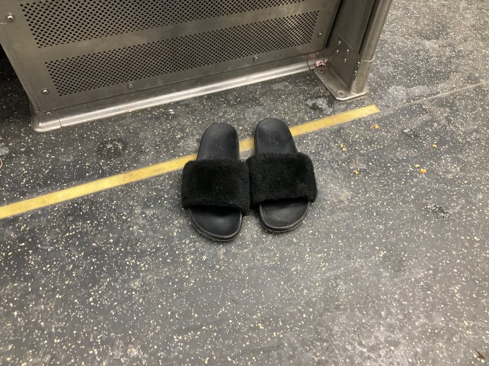 An person sleeping lying down across multiple seats in their stocking feet on the Red Line last Friday night left their slippers on the floor. Photo: John Greenfield