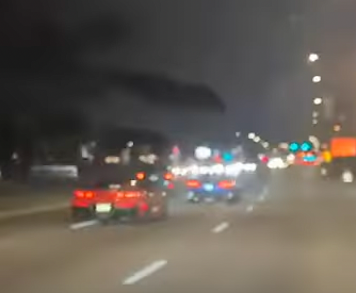 Screenshot from a dashcam video of the red Corvette driver chasing the blue Corvette driver prior to the crash.