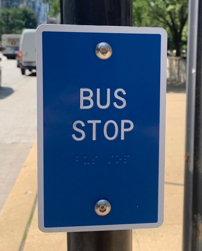 Closeup of a tactile bus stop sign with raised lettering and Braille. Photo: CTA