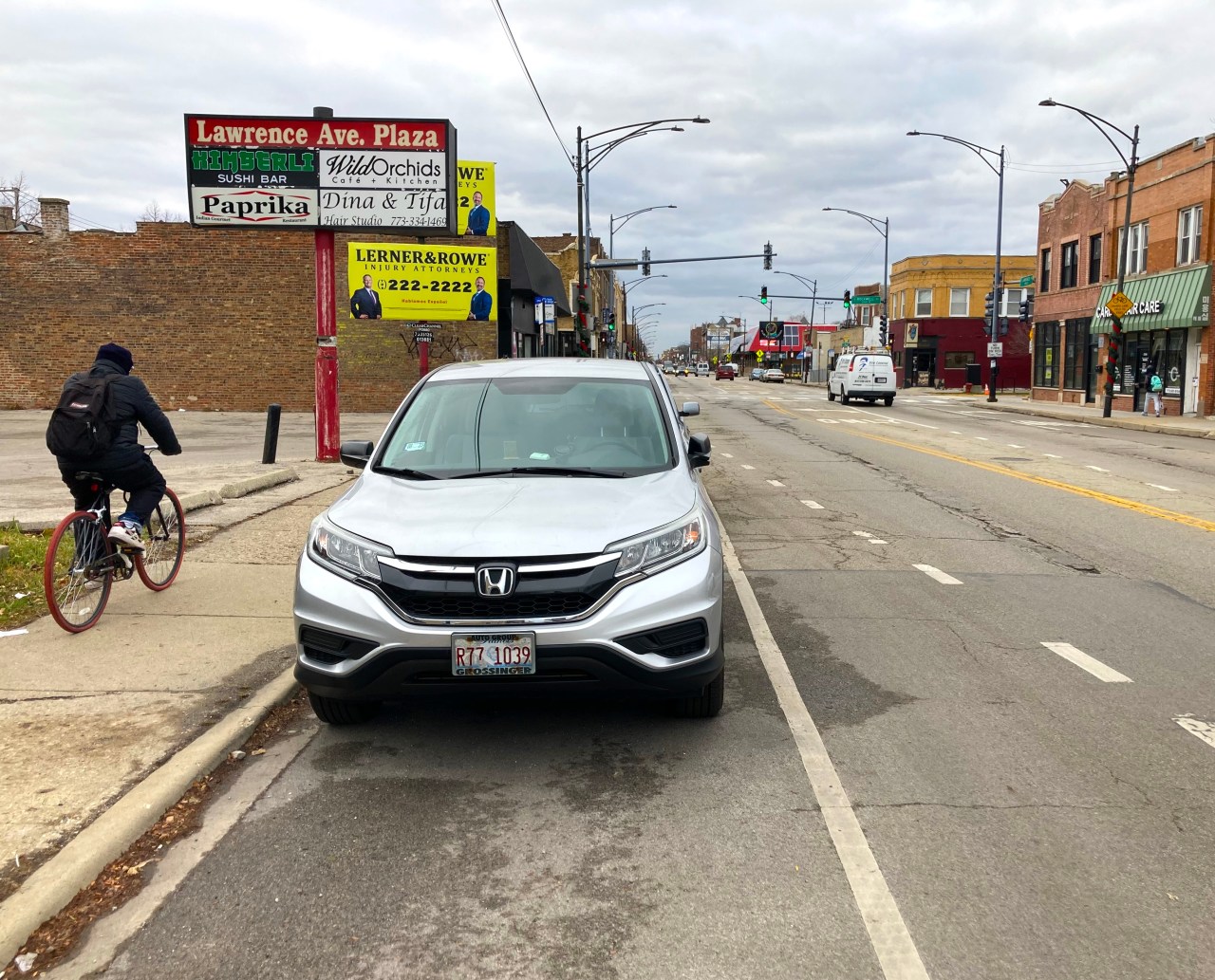 Current conditions on Lawrence Avenue near Rockwell Avenue. Rather than using the existing non-protected bike lanes, which offer no physical protection from drivers, this person opted to bike on the sidewalk. Photo: John Greenfield